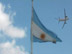 La bandera de Argentina mientras un avión vuela por encima.